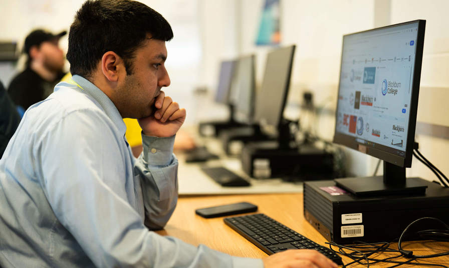 Man looking at Blackburn College logo on a PC 