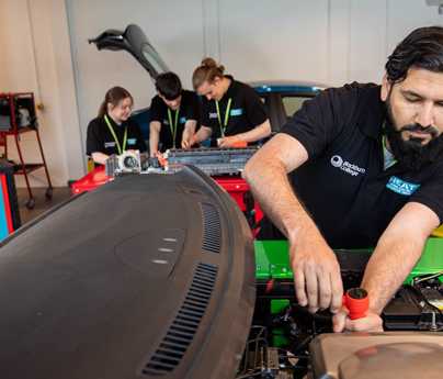 adult student working on engine of electric car
