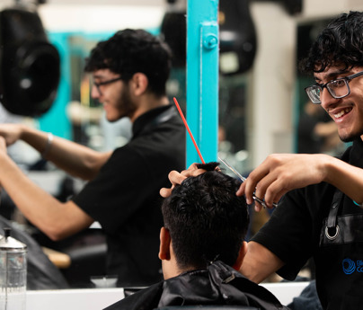 smiling barbering student cuts clients hair