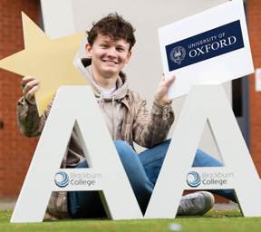 Morgan Grimshaw holding University of Oxford sign sat behind large As