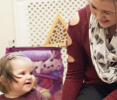 early years practitioner with baby in nursery