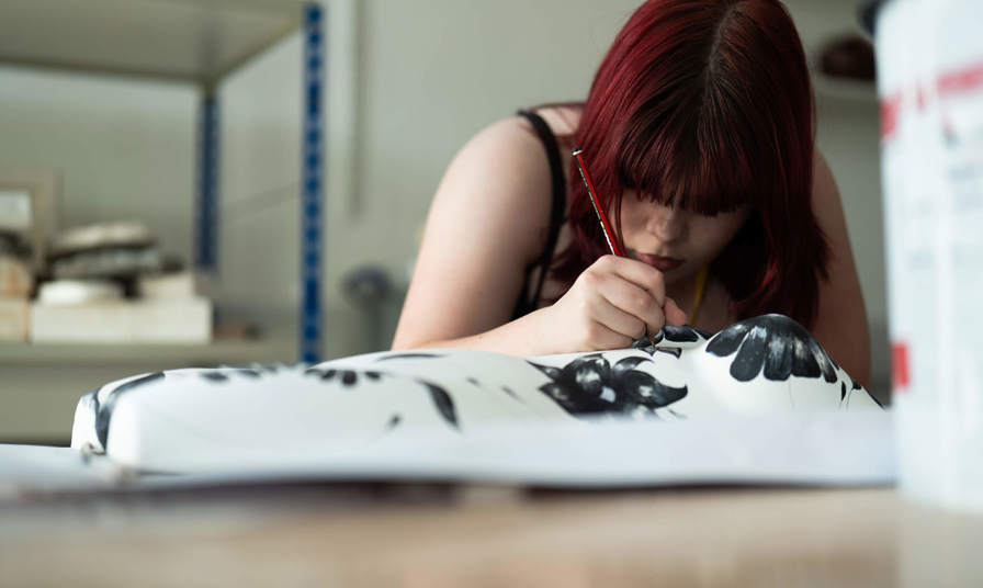 Girl painting a mannequin torso 