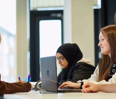 Students taking notes on paper and laptop