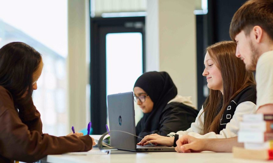 Students taking notes on paper and laptop