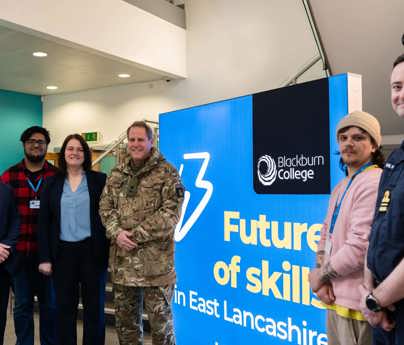 Group of people smiling to camera around lit sign reading Future of skills in East Lancashire