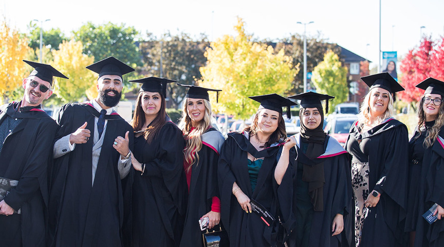 group of graduates smiling to camera one with thumbs up