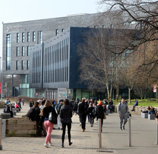 Many people walk through college campus in front of the Beacon Centre