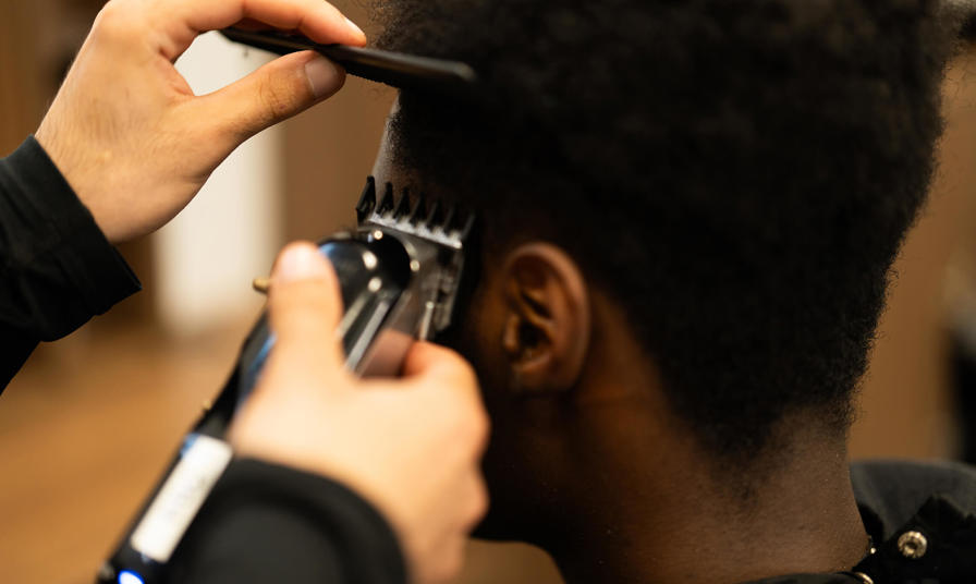 Close up photo of a student cutting hair with an electric razor 