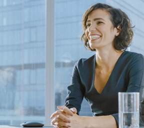 smiling woman sat assuredly talking at office desk