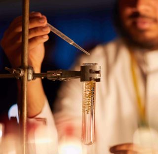 close up of science student using pipette with test tube in holder