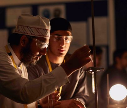 close up of student using pipette with test tube on holder in dim light