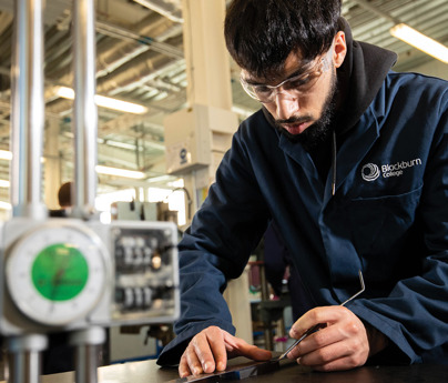 student in mechanics overalls working with engineering equipment