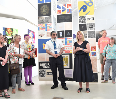 people talking to visitors to the art show stood in gallery space