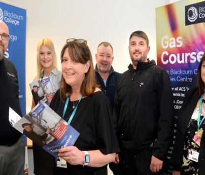 group of people smiling to camera holding Blackburn College Trades Centre booklet plus Gas Course banner
