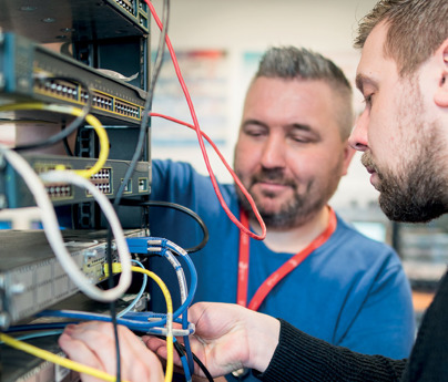 2 people looking at network cables in computer server