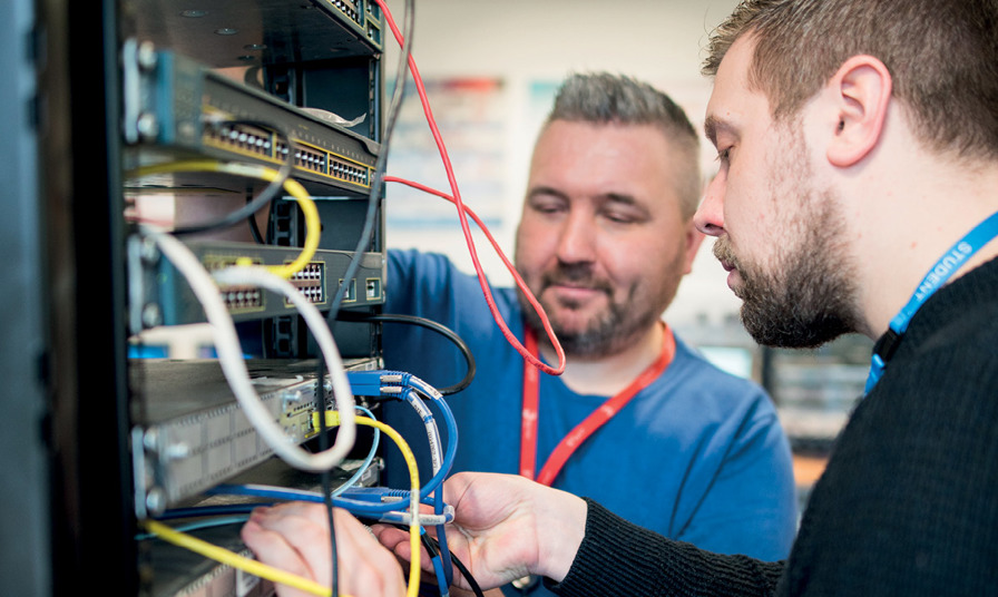 2 people looking at network cables in computer server