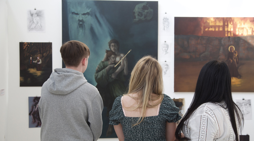 Audience admire detailed paintings on a wall at art exhibition