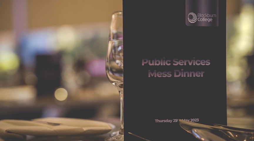 Close up of menu for Public Services Mess Dinner on table with glasses and cutlery