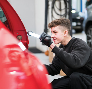 young man examines car in mechanics workshop