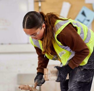 young woman using spirit level on brick wall in workshop