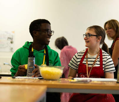 Students grating cheese and smiling