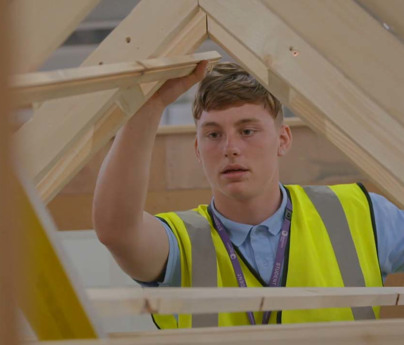 young man in hi-vis jacket surrounded by wooden beams