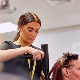 hairdressing student blow dries hair of a women