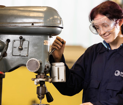 student in mechanics overalls working with engineering drilling equipment