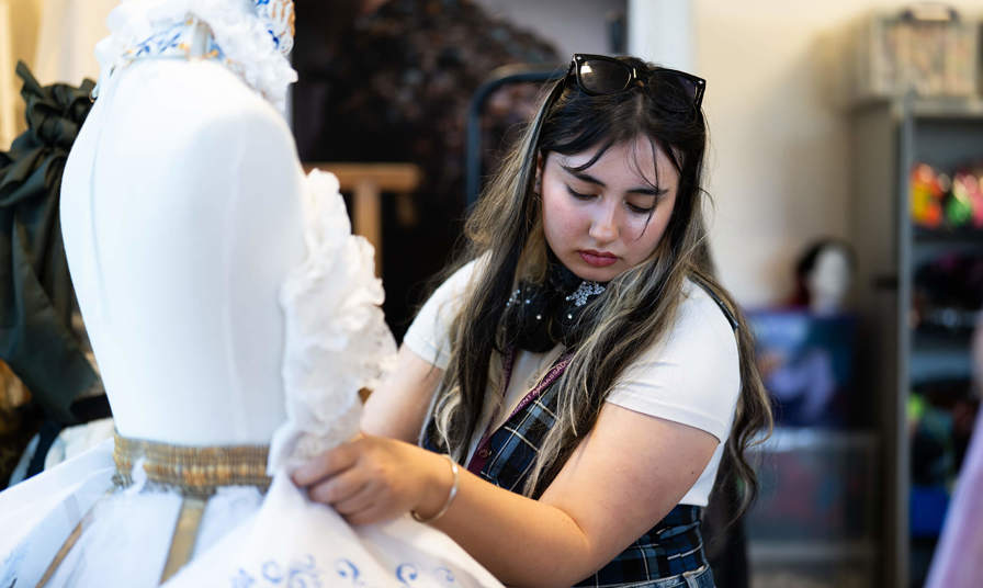 Girl stood using a sewing mannequin
