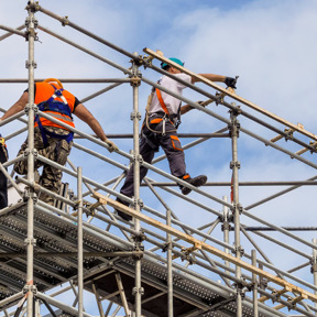 workmen in harnesses and high-vis jackets on scaffolding