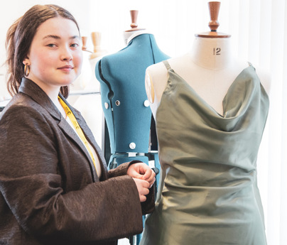 student stands with mannequin and dress
