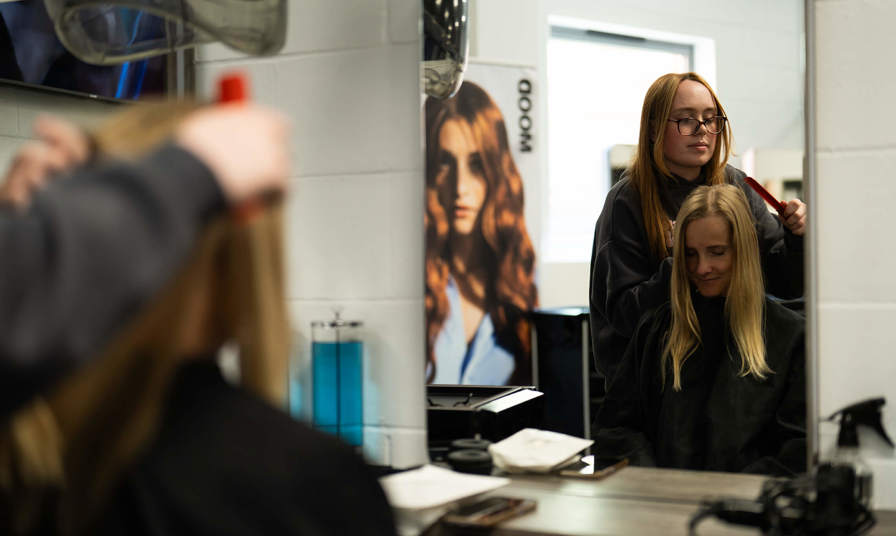 reflection of a student styling hair in a mirror 