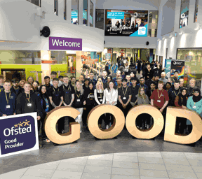 large group of people stood behind large gold letters spelling GOOD and Ofsted Good Provider signs