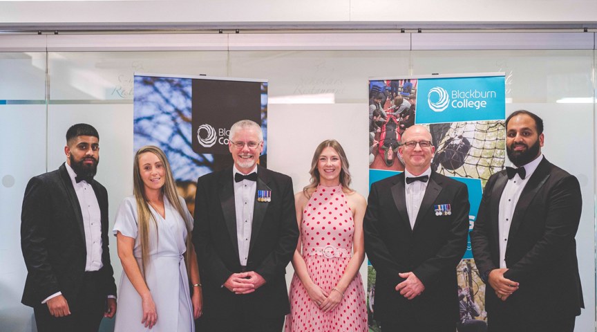 row of people in formal dinner wear smile to camera in front of blackburn college banners