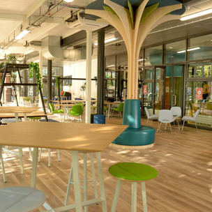 Inside Blackburn Sixth Form social space - The Pavilion. Chair and tables with plants.