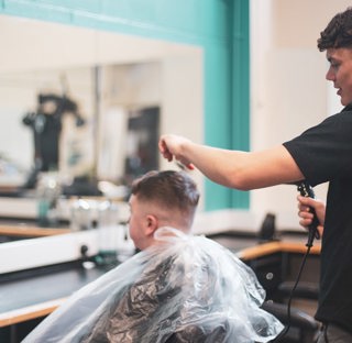 barber holds clippers and combs clients hair