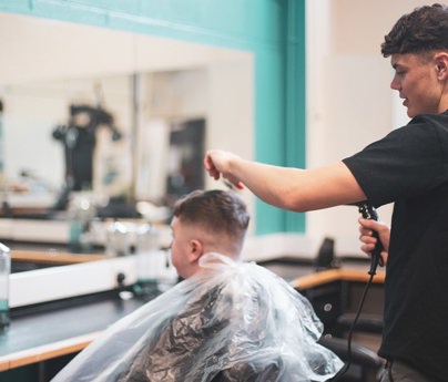 barber holds clippers and combs clients hair