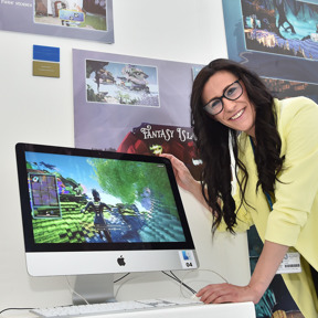 woman poses with animation graphics on mac screen at art and design show