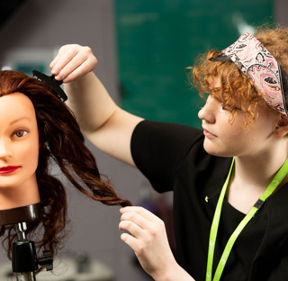 student hairdresser applies hair clips to mannequin 