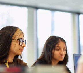 Two girls looking at laptop screen in business class