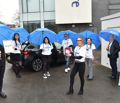 group of people stood holding umbrellas in front of car holding award with eazyseat young enterprise banner