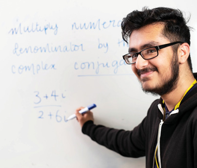 male student writes equation on white board