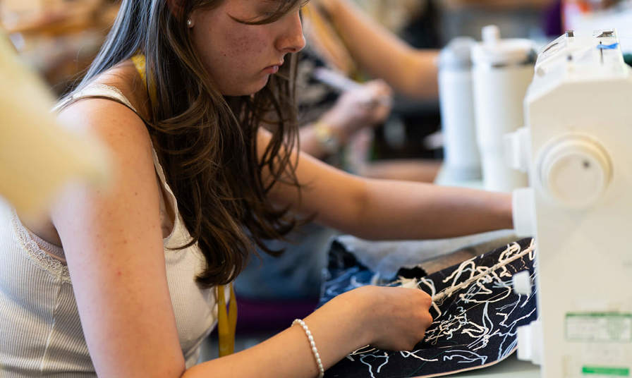 Girl sat using a sewing machine