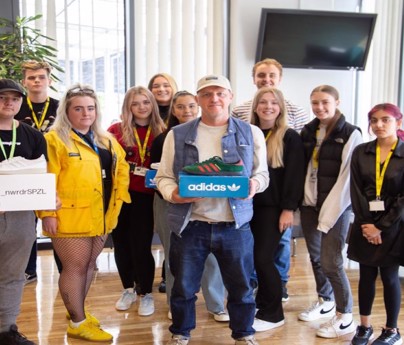 Gary Aspden holds adidas box with trainers with group of students