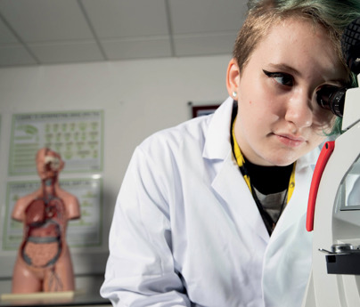 close up of female student looking through microscope