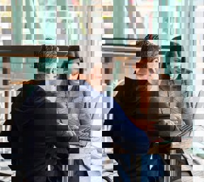 1 man and 1 woman talking looking at laptop on table