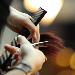 close up of cutting hair with scissors and holding comb