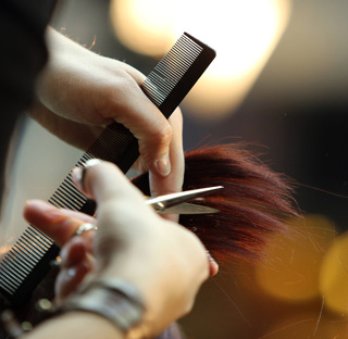 close up of cutting hair with scissors and holding comb