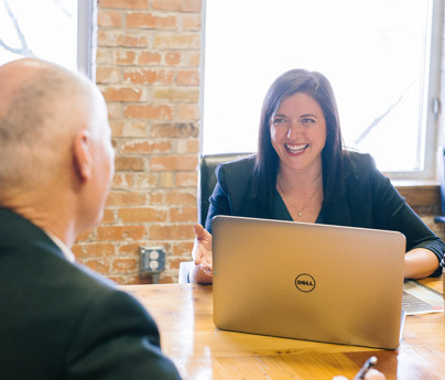 smiling woman with laptop and coffee sat across from man at table