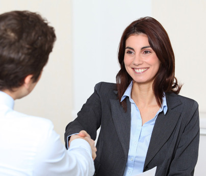 2 people shaking hands across a table in office